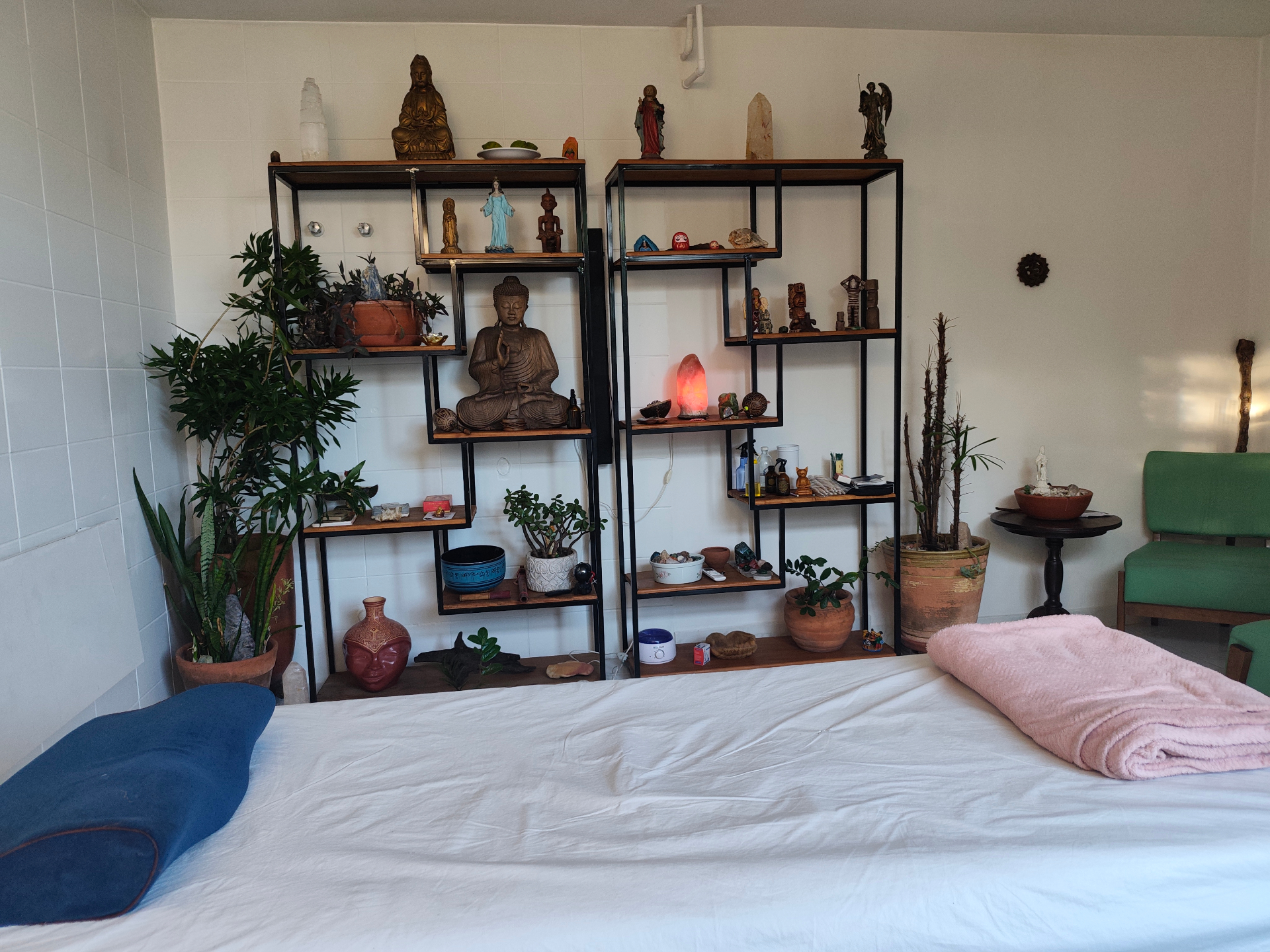 Sala de atendimento da Cura com Amor em São Paulo, com maca, plantas e altar com imagens sagradas